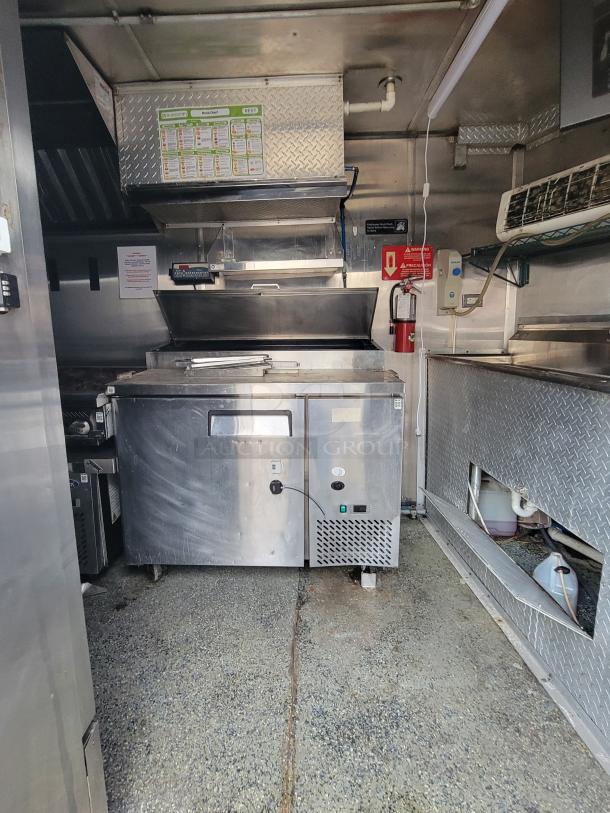 Quality Cargo Model 24 food truck kitchen interior, stainless steel appliances, grill, visible safety equipment, good condition.