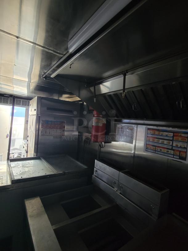 Quality Cargo Model 24 food truck kitchen, stainless steel interior with vent hood, fryers, and prep stations, good condition.