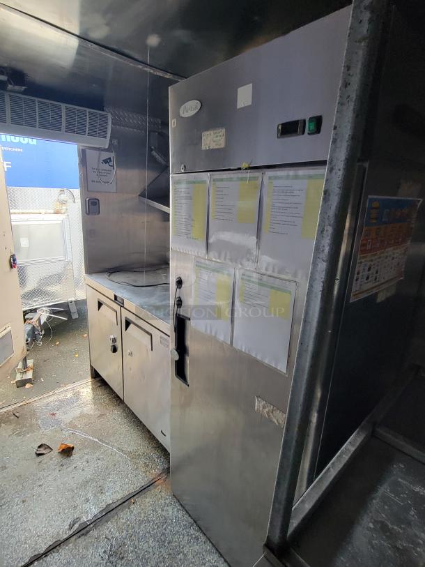 Quality Cargo Model 24 kitchen interior with stainless steel appliances, ventilation system, and visible signage.