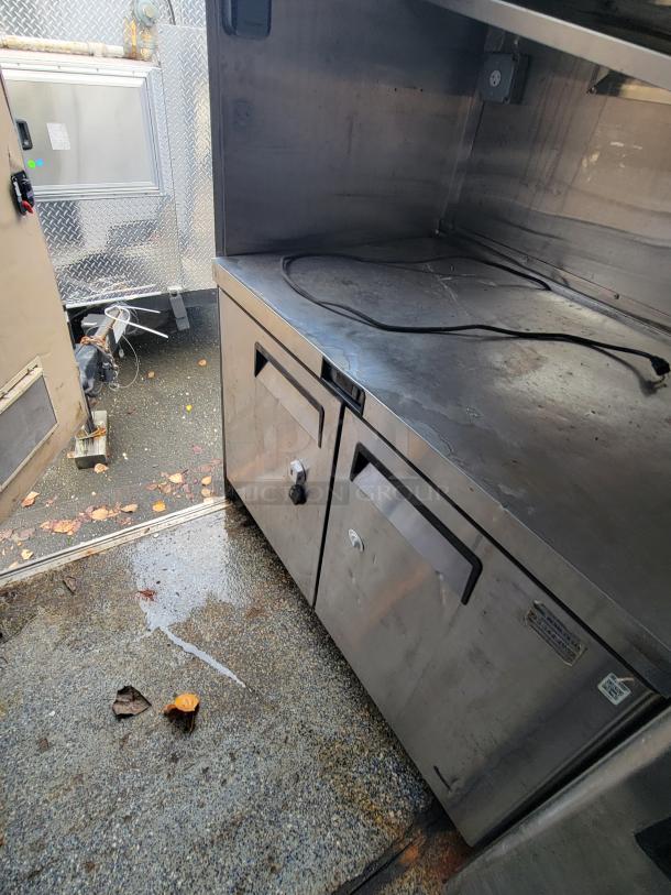 Quality Cargo Model 24 stainless steel workstation. Features dual cabinets, sturdy condition, visible power outlet inside.