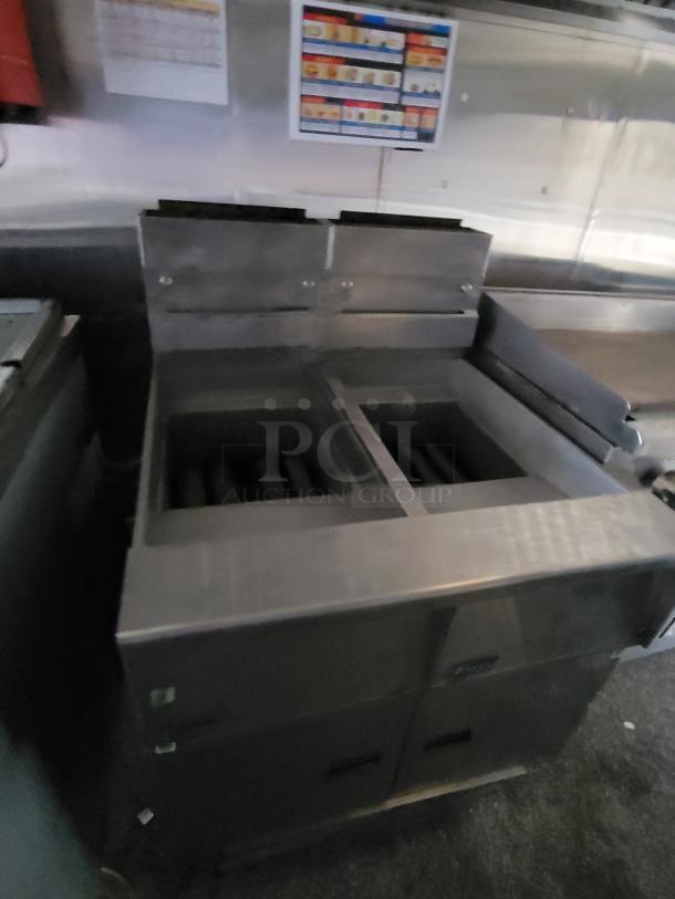 Industrial stainless steel double fryer by Quality Cargo, Model 24, in used condition with visible controls and storage below.
