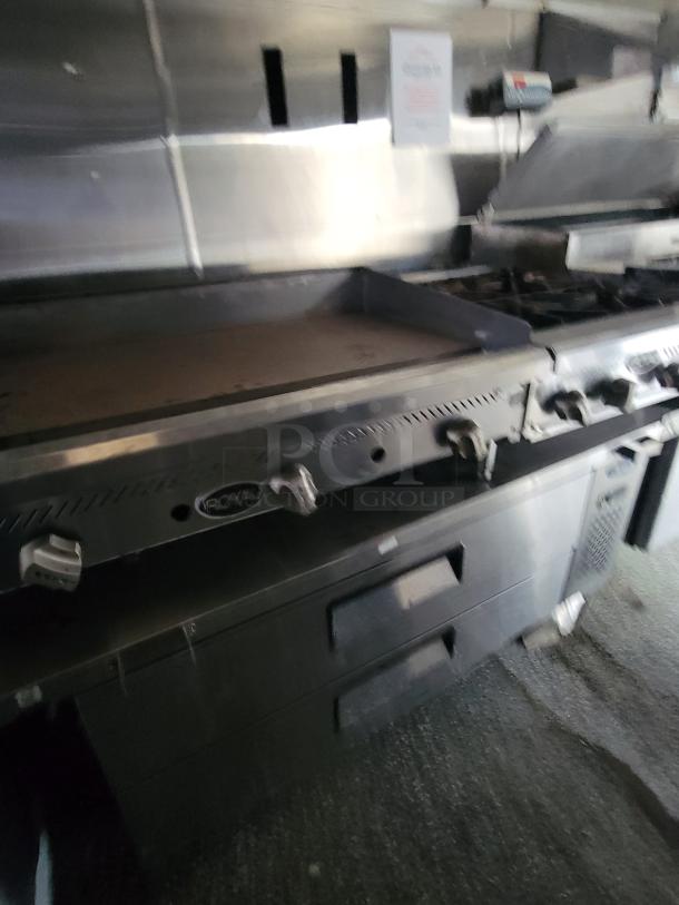 Commercial flat-top griddle by Quality Cargo, Model 24, stainless steel, integrated dials, moderate wear.