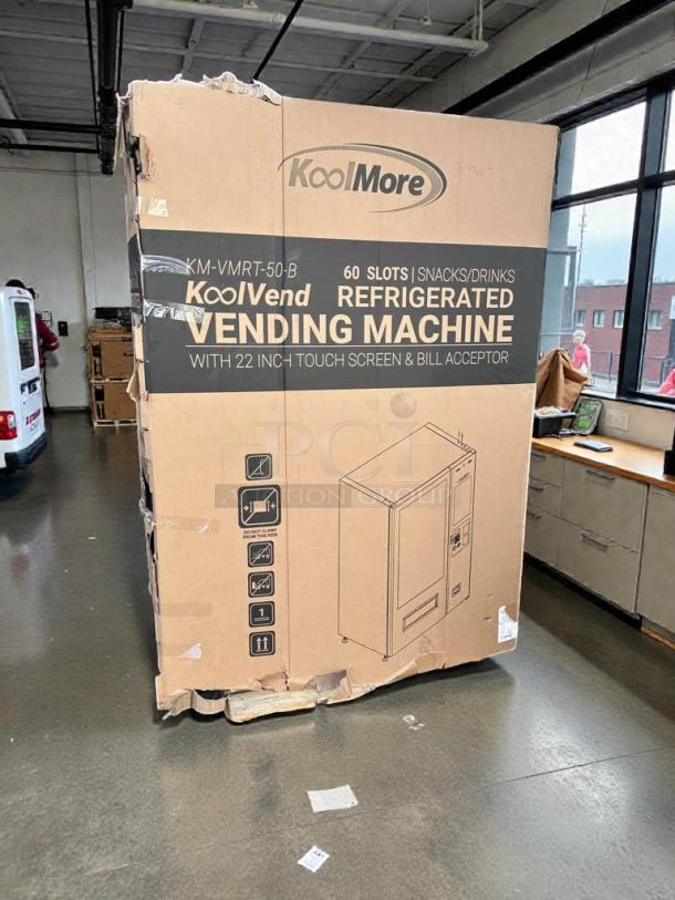 KoolMore KoolVend refrigerated vending machine in box, model KM-VMRT-50-B, holds 60 slots, and includes a 22-inch touch screen.