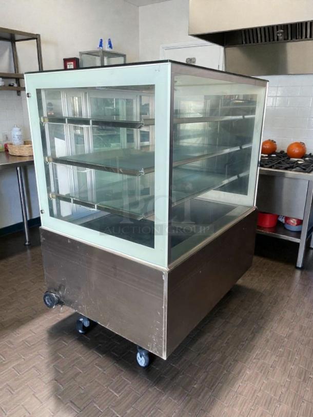 Immaculate commercial refrigerated glass display case, 115V, single phase, fully tested, on wheels, ideal for showcasing goods.