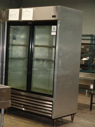 True 1/10" two-section reach-in refrigerator with two sliding glass doors, 115v. Stainless steel exterior, visible labels.