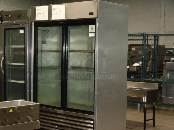 True 1/10" reach-in refrigerator with two sliding glass doors, 115v, stainless steel, excellent condition, interior shelving.
