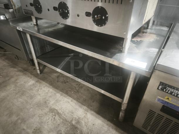 Stainless steel commercial worktable with 4" backsplash, adjustable feet, dual shelves, ideal for food prep, premium condition.