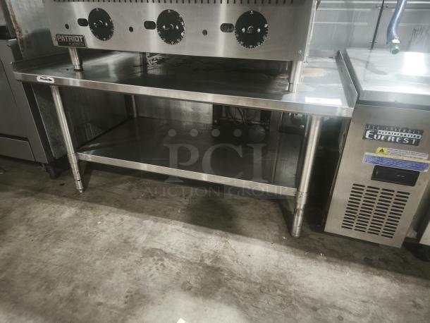 Stainless steel commercial worktable with 4" backsplash, adjustable feet, shelf, and Patriot nameplate. Excellent condition.