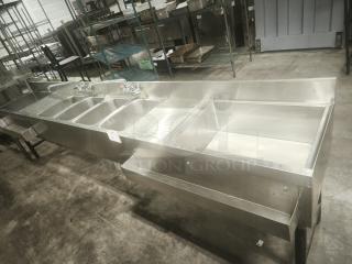 Stainless steel 4-bay bar sink in premium condition, with attached faucets and drainboards, ideal for commercial use.