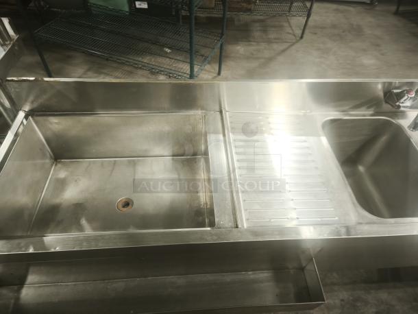 Stainless steel 4-bay bar sink in premium condition, featuring a large basin, drainboard, and integrated faucet. Ideal for commercial use.