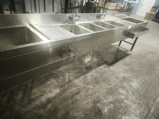Stainless steel 4-bay bar sink in premium condition. Features individual faucets and integrated drainboards. Ideal for commercial use.