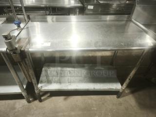 Stainless steel worktable with manual table-mounted can opener, used, sturdy design, lower storage shelf, ideal for kitchens.