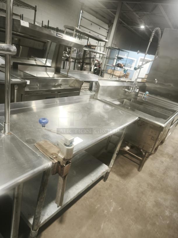 Heavy duty stainless steel worktable with manual table-mounted can opener, featuring sturdy legs and lower shelf; well-maintained.