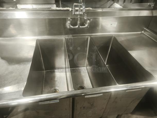 Heavy-duty stainless steel butcher 3-compartment sink with integrated backsplash, dual faucets, and visible drain areas.