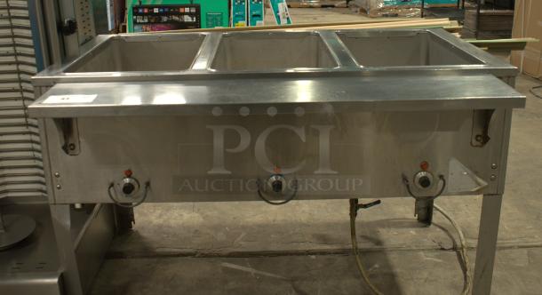 Heavy duty natural gas hot food table with three wells, stainless steel, three control knobs, rugged condition.