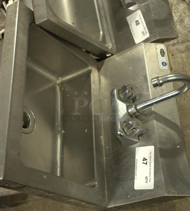 Stainless-steel commercial hand washing sink, heavy duty, with dual knobs and label marked "47 QTY." Visible signs of use.