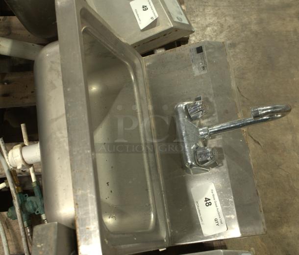 Stainless-steel commercial hand washing sink, heavy-duty, with dual faucet knobs, auction tag visible.