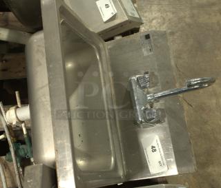 Stainless-steel commercial hand washing sink, heavy-duty, with dual faucet knobs, auction tag visible.