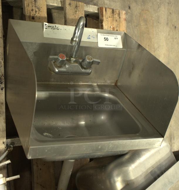 Stainless-steel commercial hand washing sink, heavy duty, features dual faucets, sturdy design, slight wear.