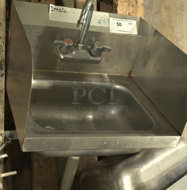 A stainless-steel commercial hand washing sink with dual faucets. Heavy-duty design, signs of use, auction tag visible.