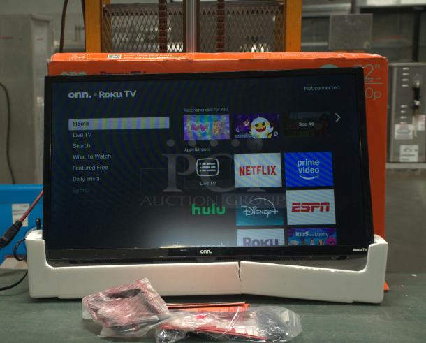 BRAND NEW Onn 32” 720P HD Roku Smart TV, display on, remote in packaging, boxed behind.