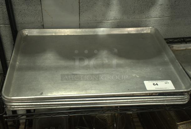 Heavy-duty full-size silver baking sheet pan, stacked, with visible handling marks, auction label "64 QTY" on edge.