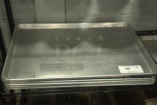 Heavy-duty full-size silver baking sheet pan, stacked, with visible handling marks, auction label "64 QTY" on edge.