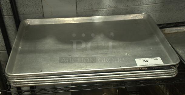 Full-size silver baking sheet pan, heavy duty, stack of four, used condition, visible auction tag marked "64 QTY".