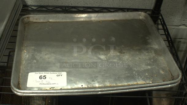 Heavy-duty half-size baking sheet pan, silver, showing signs of wear. Tag indicates auction lot 65, from PCI Auctions.