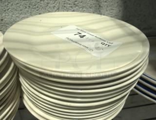 8" vintage-style plates in a stack, cream color, lightly used condition. Auction label indicates quantity of 74.