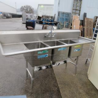 Stainless steel 3 compartment sink with faucet, left/right drain boards, 88x26x45.5 inches, outdoor setting, visible pipe connections.