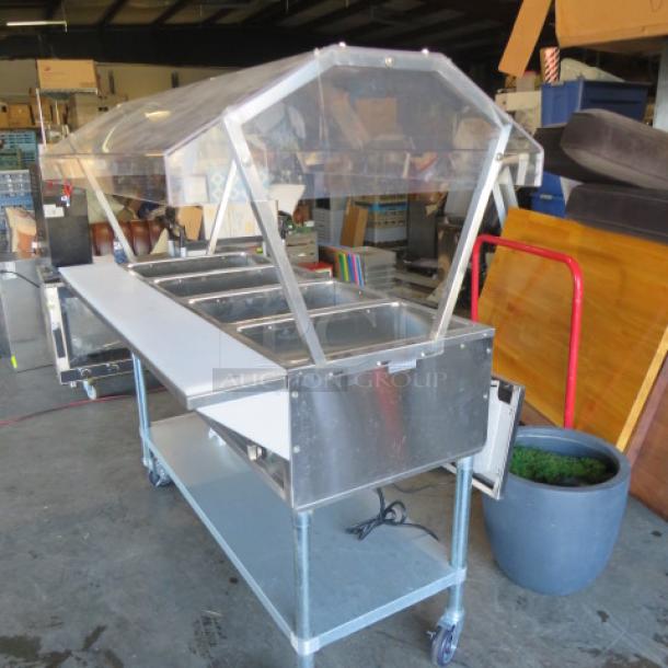 Servit 4-well electric steam table with sneeze guards, cutting board, stainless steel under shelf, model 423EST4WO500, on casters.
