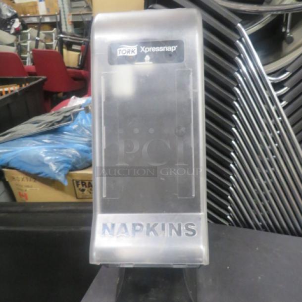 Tork Xpressnap Napkin Dispenser 32XPS, transparent, good condition, visible branding, suitable for commercial use.