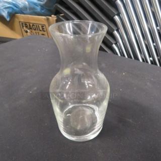 Clear glass carafe, hourglass shape, used condition. No visible branding or markings. Smooth surface, no chips or cracks.