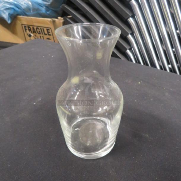 Clear glass vase with a flared neck and rounded body. Appears to be in good condition against a dark background.
