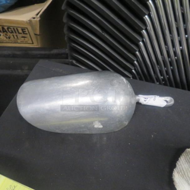 Alt text: Large 85oz aluminum scoop, shown on a table. Sturdy design with a smooth handle, in good condition.