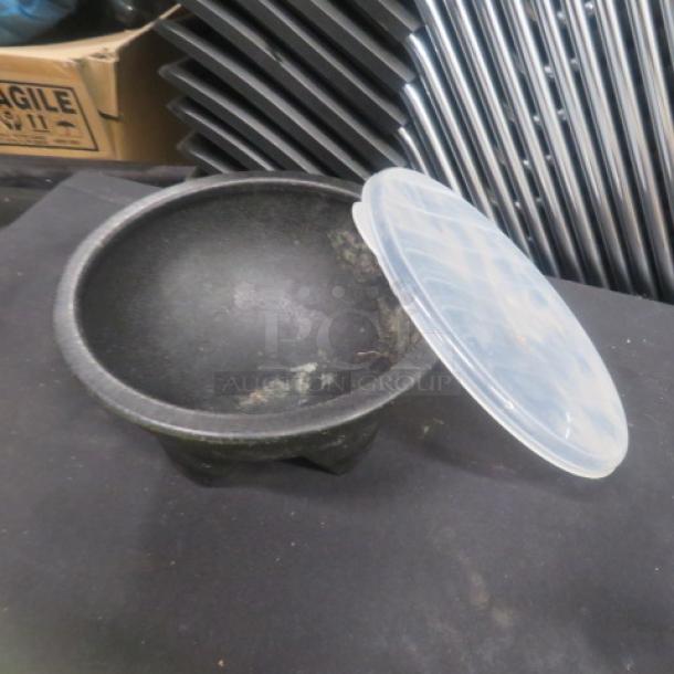 45oz black molcajete bowl with plastic lid, in used condition. Suitable for serving or grinding, features sturdy legs.