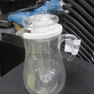 Clear glass pitcher with a handle, white lid, and pull-out core. Good condition. Auction label "388" visible.