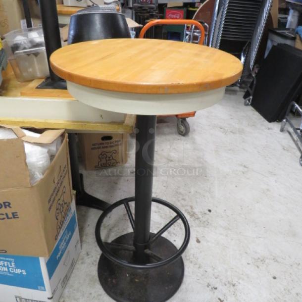Wooden bar height table with pedestal base and footrest, 24x43 inches, sturdy condition.