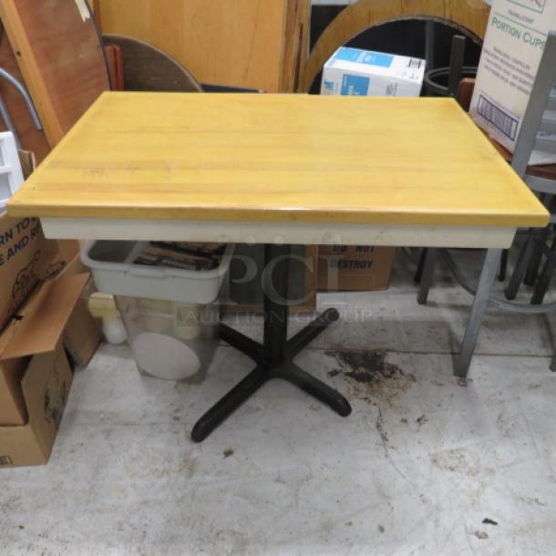 Wooden tabletop on a black pedestal base, measuring 42x28x32.5 inches. Light wear, sturdy construction.