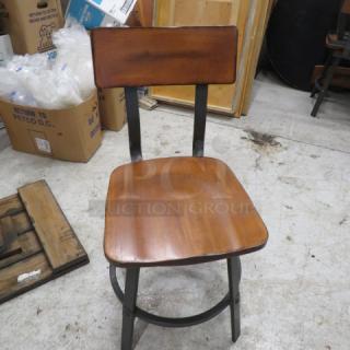 Industrial black metal chair with wooden seat and back. Minimalist design, sturdy construction. Condition appears good.