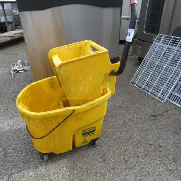 Yellow mop bucket with wringer, used condition, two compartments, handle and wheels, visible caution signage.