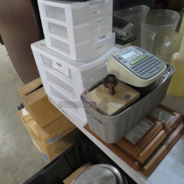 One lot of office supplies including storage drawers, label maker, stamp, frames, and various items in a basket, in used condition.