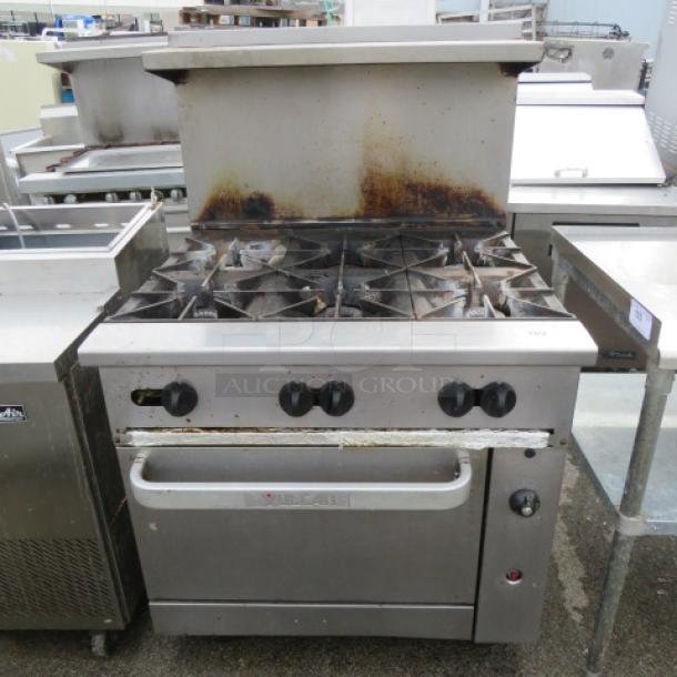 Vulcan 6 burner natural gas range with stainless steel overshelf, 2 racks on casters, 36x34x59 inches, used condition.