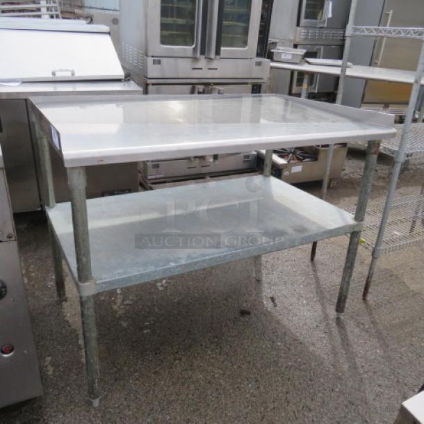 Stainless steel table with under shelf, measuring 49x32x37.5 inches. Good condition, suitable for industrial or kitchen use.