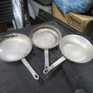 Set of three 8-inch sauté pans with handles, showing signs of wear and discoloration, indicating prior use.