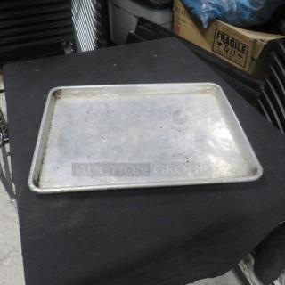 1/2 size aluminum sheet pan, used condition with visible surface scratches, sturdy build, industrial kitchen quality.