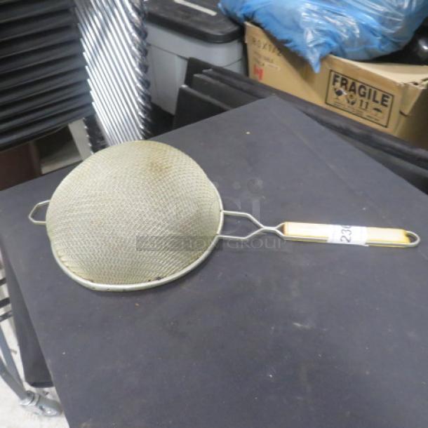 Vintage mesh strainer with metal frame and wooden handle, slightly worn condition, labeled "234."