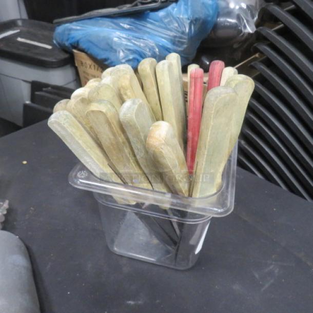 One lot of steak knives with wooden handles in various colors, stored in a clear container. Used condition.