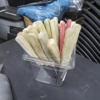 One lot of steak knives with wooden handles in various colors, stored in a clear container. Used condition.